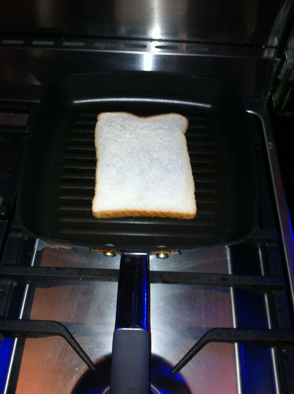 Heat the griddle pan. Butter both sides of bread and add one slice of bread to the pan.