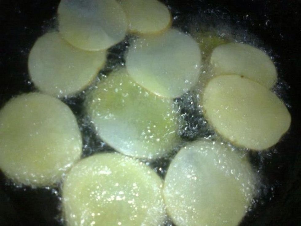 Heat the oil and gently drop a few potato slices into the hot oil until the chips are evenly browned