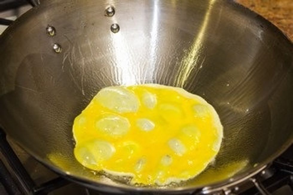 Heat the wok over medium high heat. When it\u2019s getting hot, add the oil. When you see white smoke coming off from the wok, add the egg in the wok.