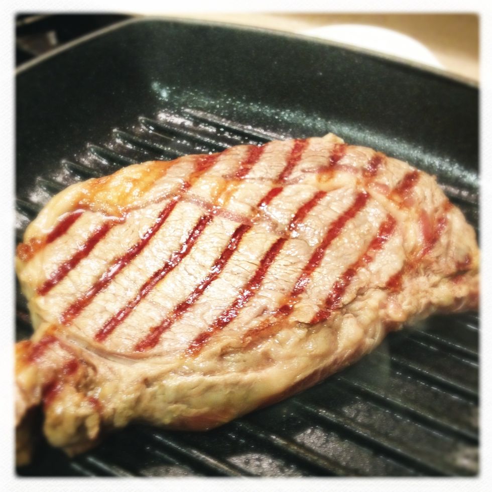 heat up the grill at high flame for a minute, use the extra fat from the steak to melt evenly on the surface of the grill (don't use oil).  start grilling first side of the steak for 2-3 mins