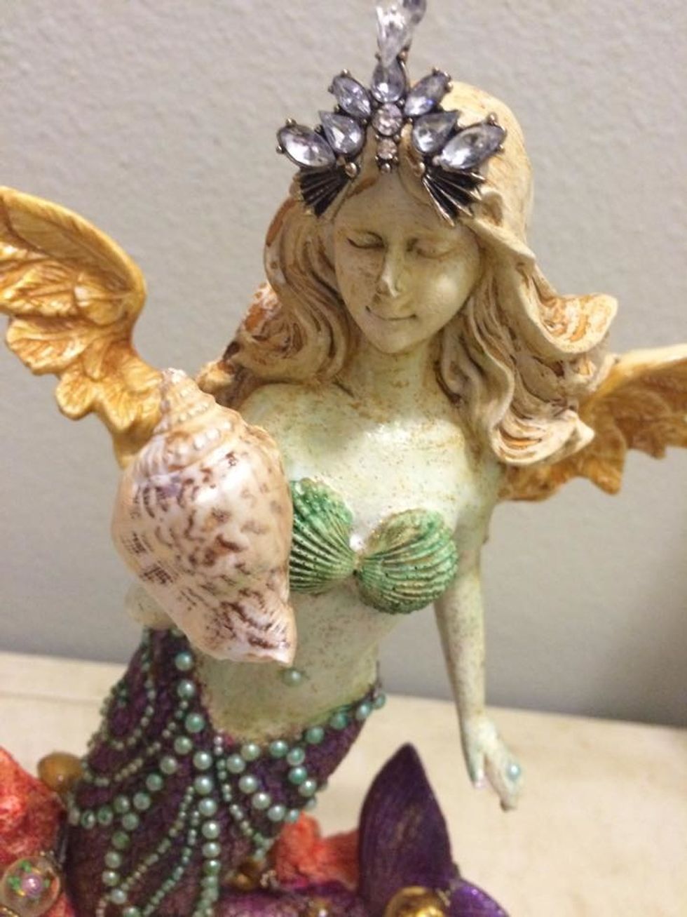 Her head piece is from an old earring I had. It fit perfectly on top of her head. I glued this on with E6000 Jewelry glue. It dries much faster than regular E 6000 so you dont have to hold it forever.