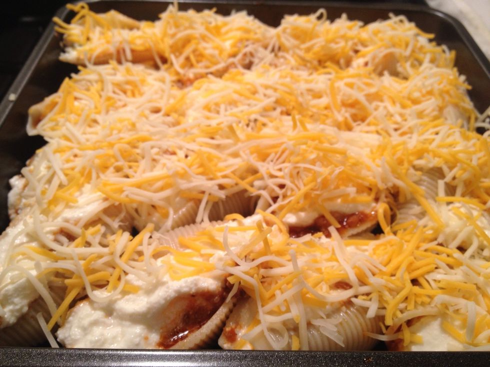Here are the shells almost ready for the oven. Sprinkle the stuffed shells with shredded cheese. I used a Mexican blend but use mozzarella or whatever you wish.