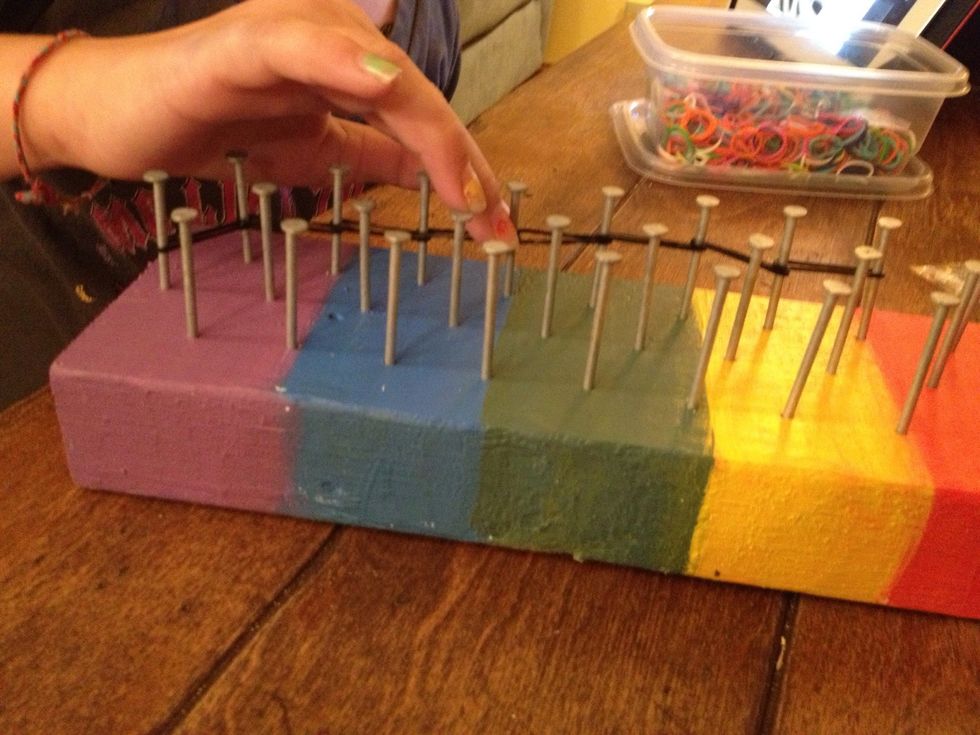 Here is my daughter starting to put the silicone bands on the nails to develop her pattern. She's making http://Snapguide.com/guides/make-a-starburst-rainbow-loom-bracelet  from user Alyssa Mead