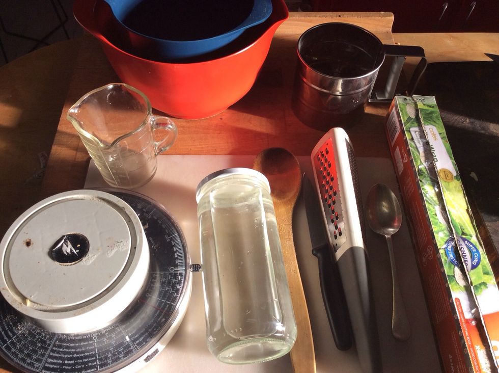 Here's the equipment that you need. Medium bowl, mixing bowl, flour sifter, measuring jug, scale, wooden spoon, knife, grater, tablespoon, cling wrap and rolling pin (jar full or water)