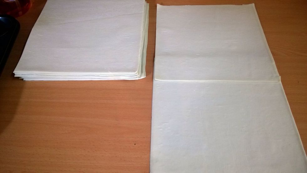 Here's the fun part. If you just had a lick of the custard, wash you hands again. So we want to overlap a few sheets of puff pastry. Keep the plastic on the first sheet.