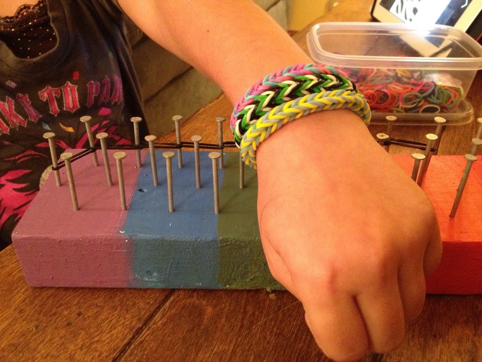 Here she is displaying some bracelets that she made using her loom. She used a crochet hook that we already had on hand to help ease the bands over the pegs, or nails.