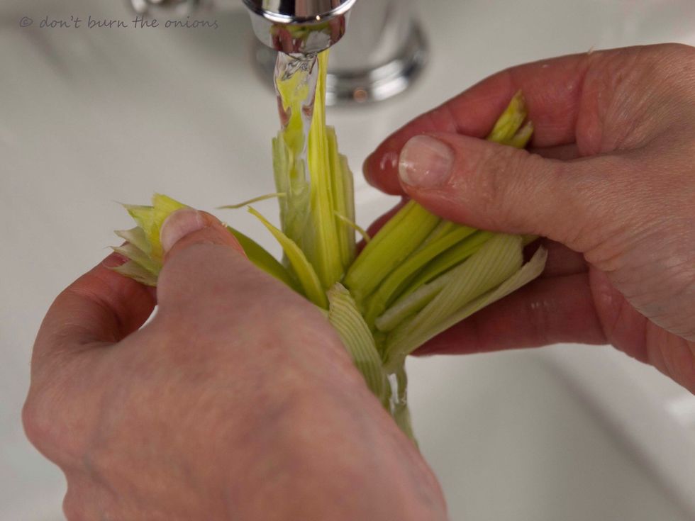Hold base under running water separating the leaves to wash away any soil.