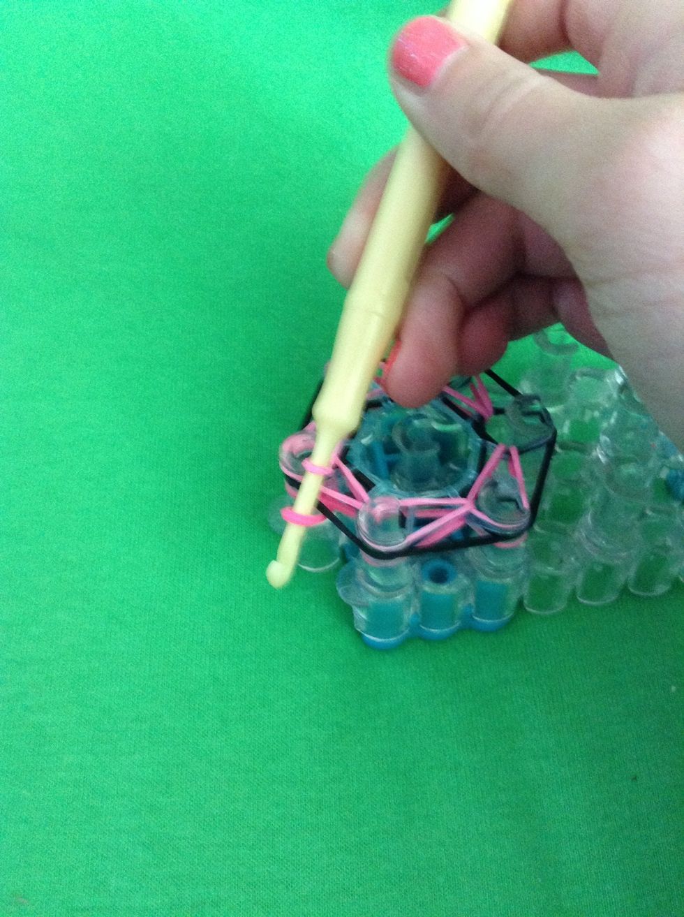 Hold on to the bottom of the rubber band and pull the top part through all the other rubber bands and put the bottom part on the hook like so