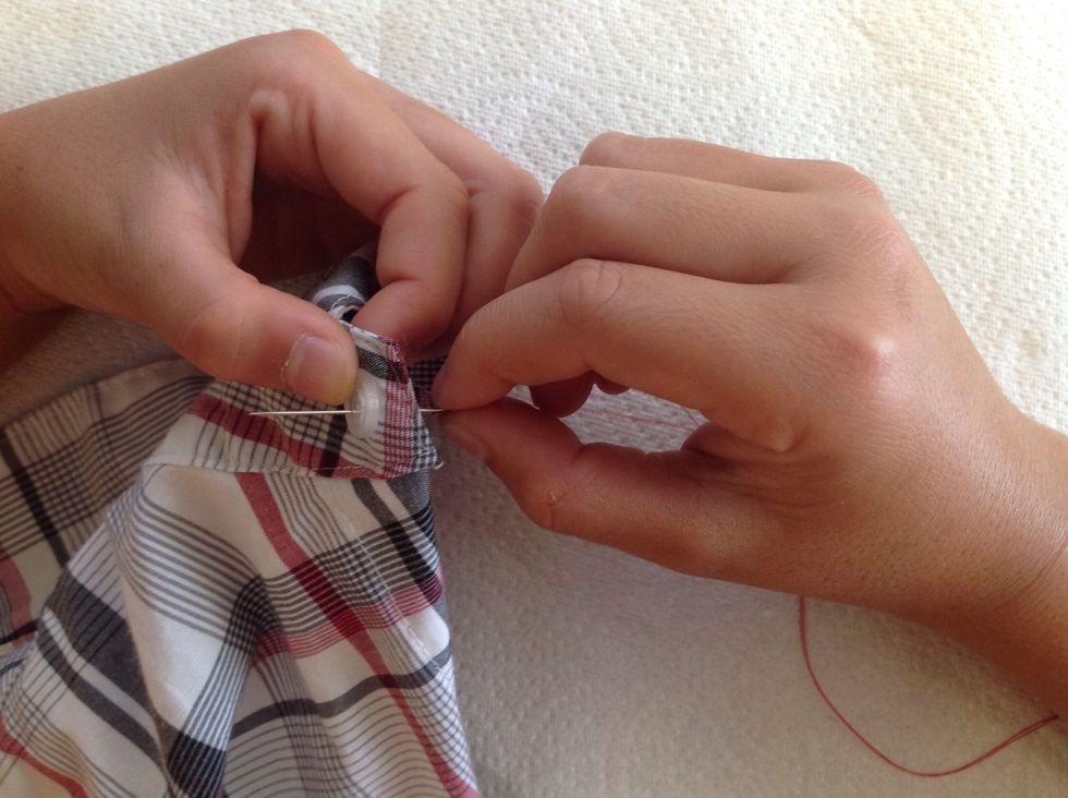 Hold the button making sure that the button holes are in a square formation while you bring the needle up through the fabric and bottom right hole, pulling thread completely through until taut.