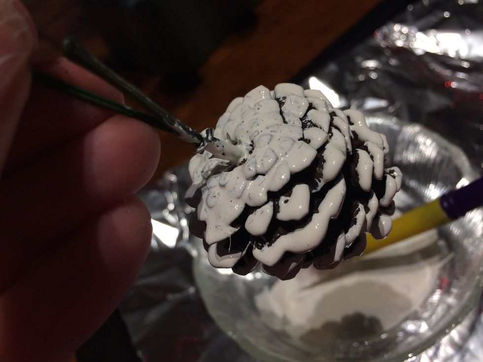 Hold the cone upside down and paint the bottom. Then brush the paint on the undersides of the scales.