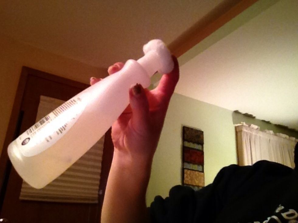Hold the cotton ball over the top of the nail polish remover bottle. Hold so no liquid will fall out and tip the bottle so that the remover will go on the cotton ball.