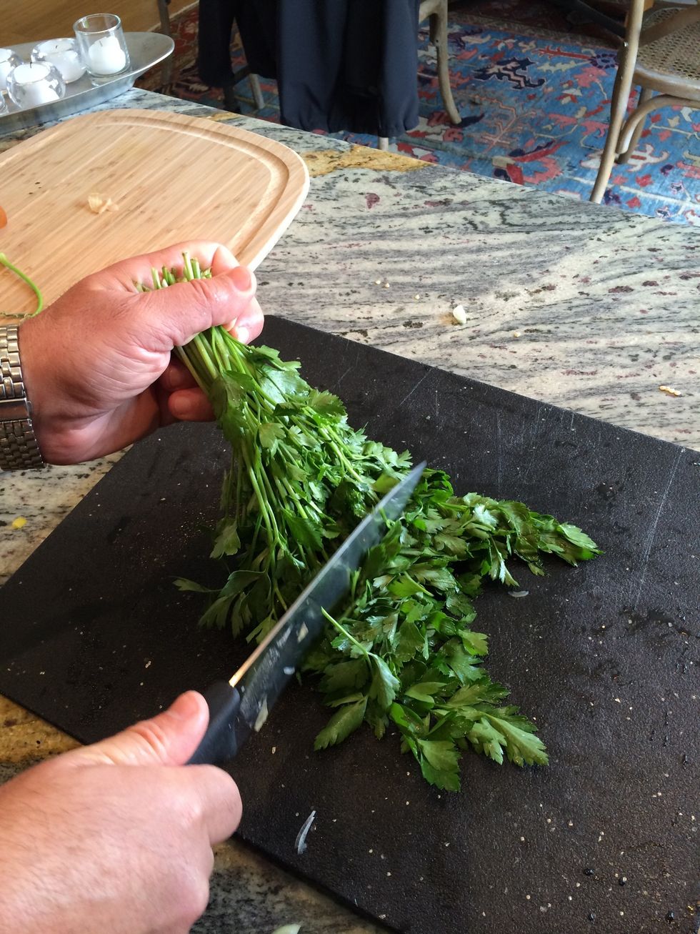 Hold the entire bunch by the stems with the leaves hanging down on the cutting board.