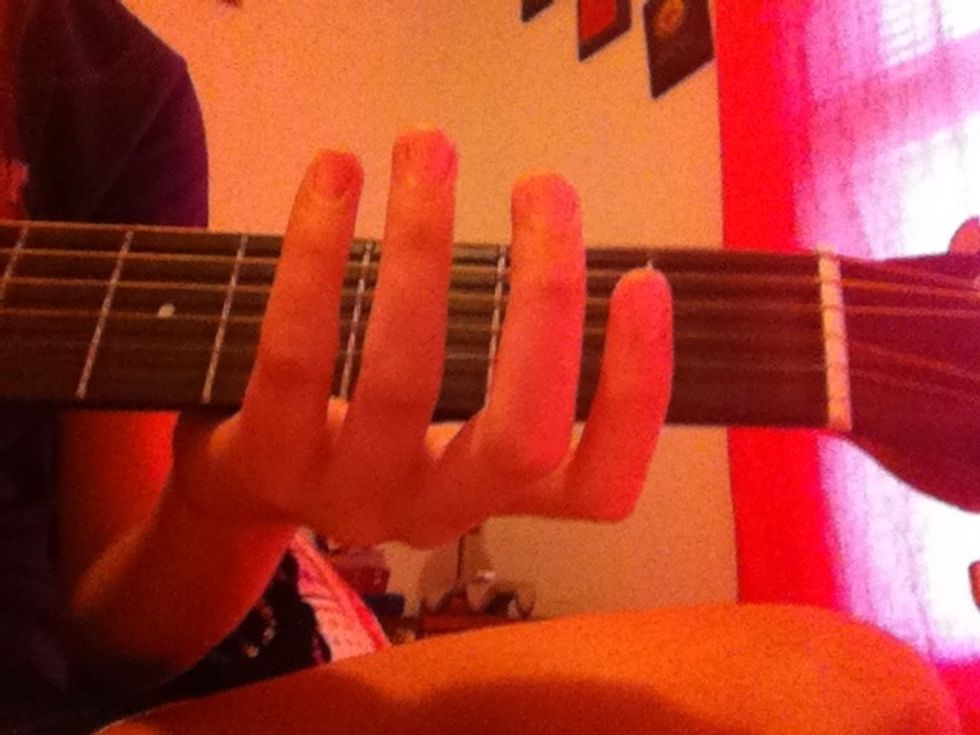 Hold the guitar near the first fret(the strings near the top of the guitar)