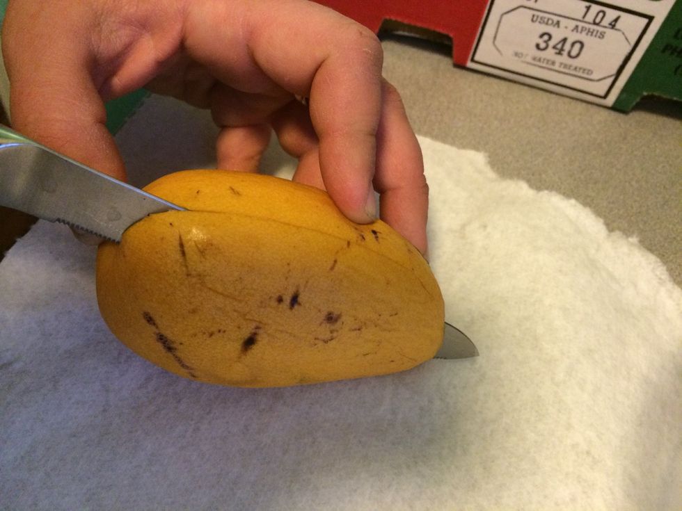 Hold the mango long ways, cut lengthwise just left or right of center (pit)