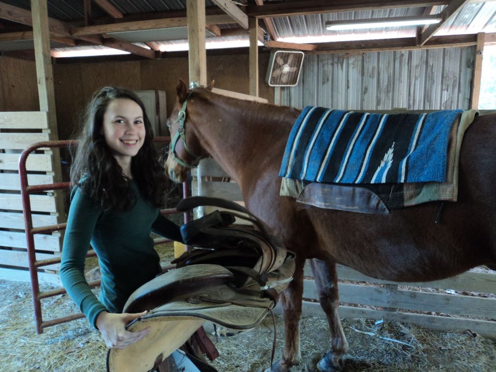 Hold the saddle with the stirrup down facing you and the stirrup on the horn facing the horse.