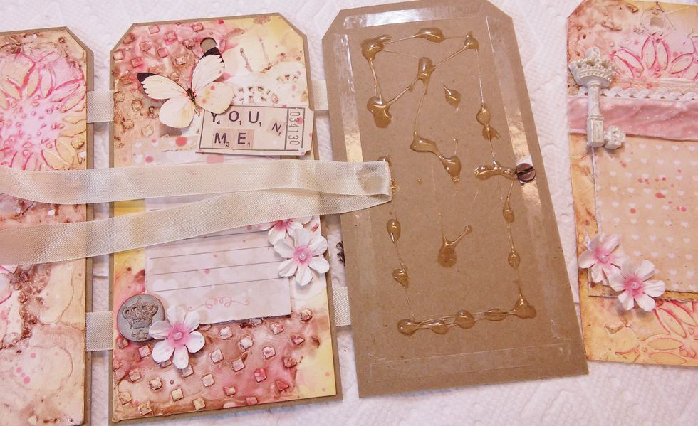 Hold up on the last one. We need to add our tying ribbon closure. A couple of feet in ribbon length is great. Fold it in half and stick it to left side of the last tag base, and put on the tag.