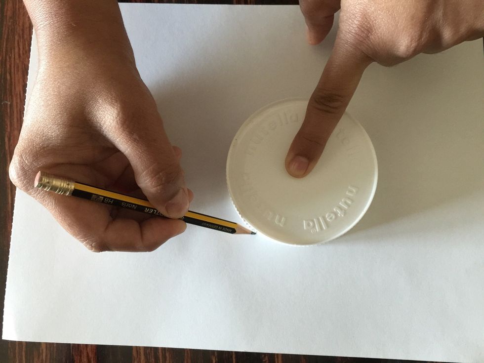 Hold your pencil and place it close to the rim of the lid.