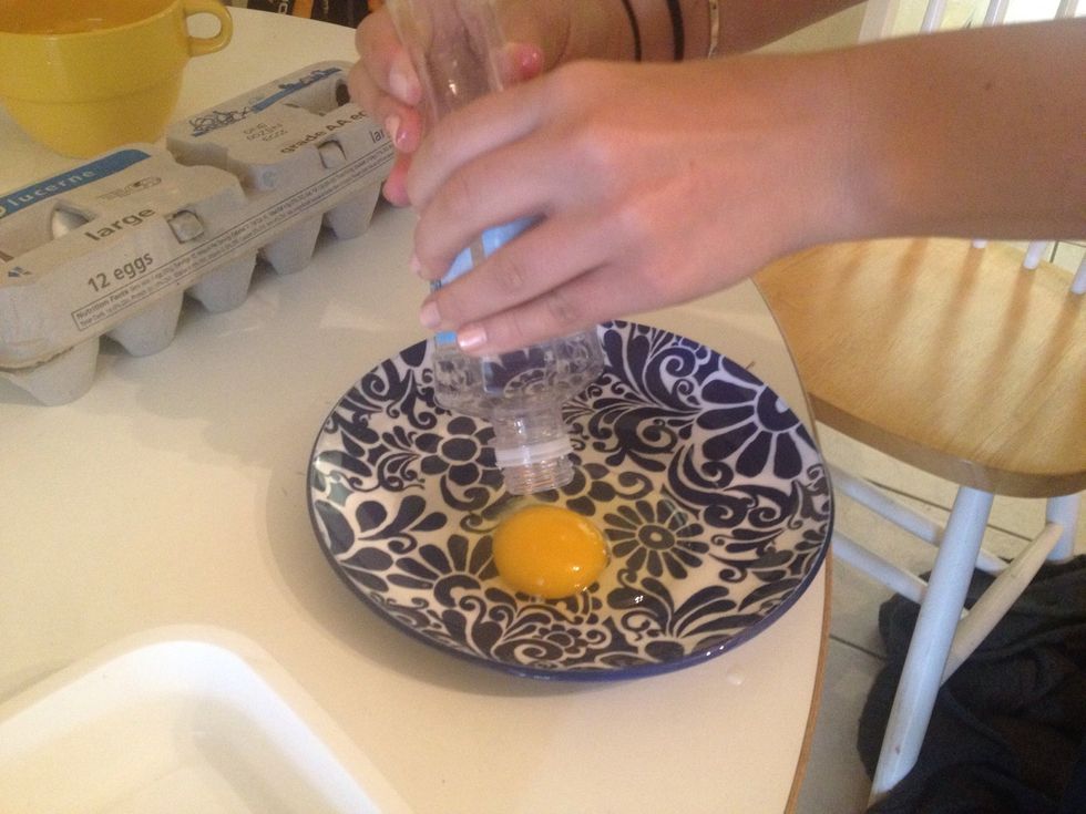 Hold your plastic bottle right above the egg and lightly squeeze. When you release the pressure, the yolk will magically slurp into the bottle. It will stay in until you squeeze the bottle again.