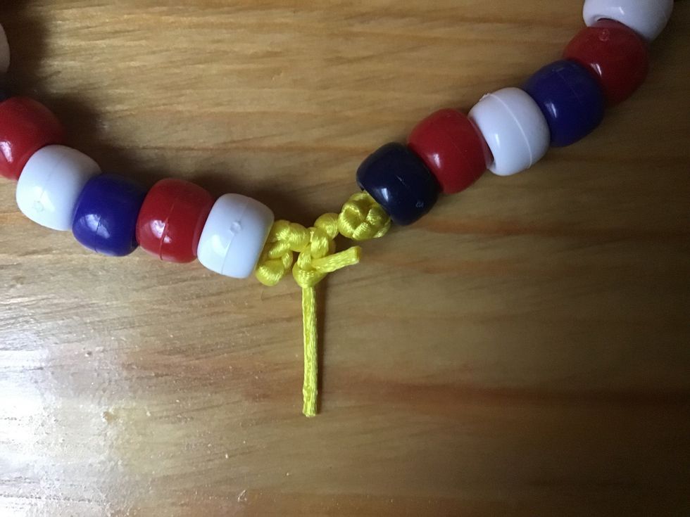 hold your strings and tie them together and your knot should look like this. Repeat this about three times