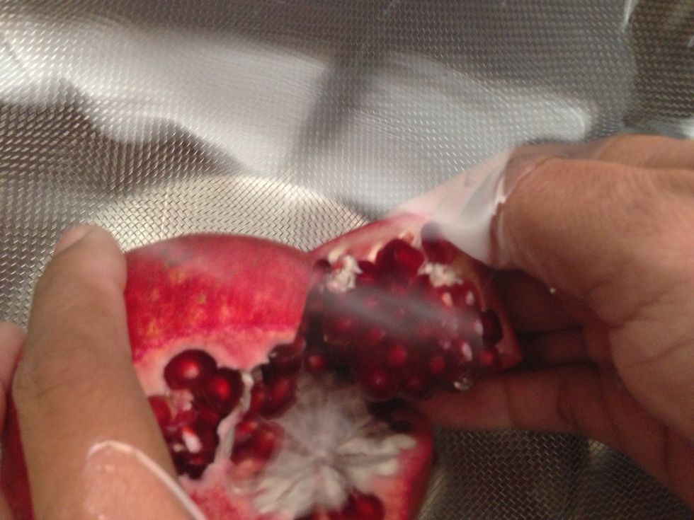Holding pomegranate under water in the bowl, gently pull apart and remove seeds without popping them as much as possible. Some will pop, but it's ok.