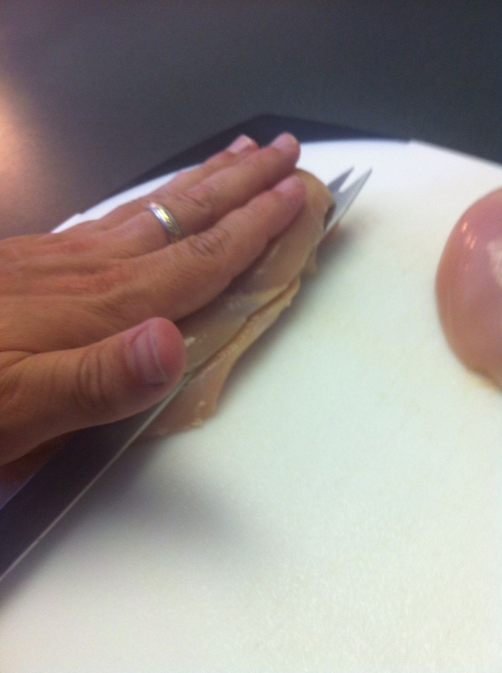 Holding the breast flat, cut the chicken in half evenly with the knife parallel to the board. KEEP YOUR FINGERS UP AND OUT OF THE WAY!