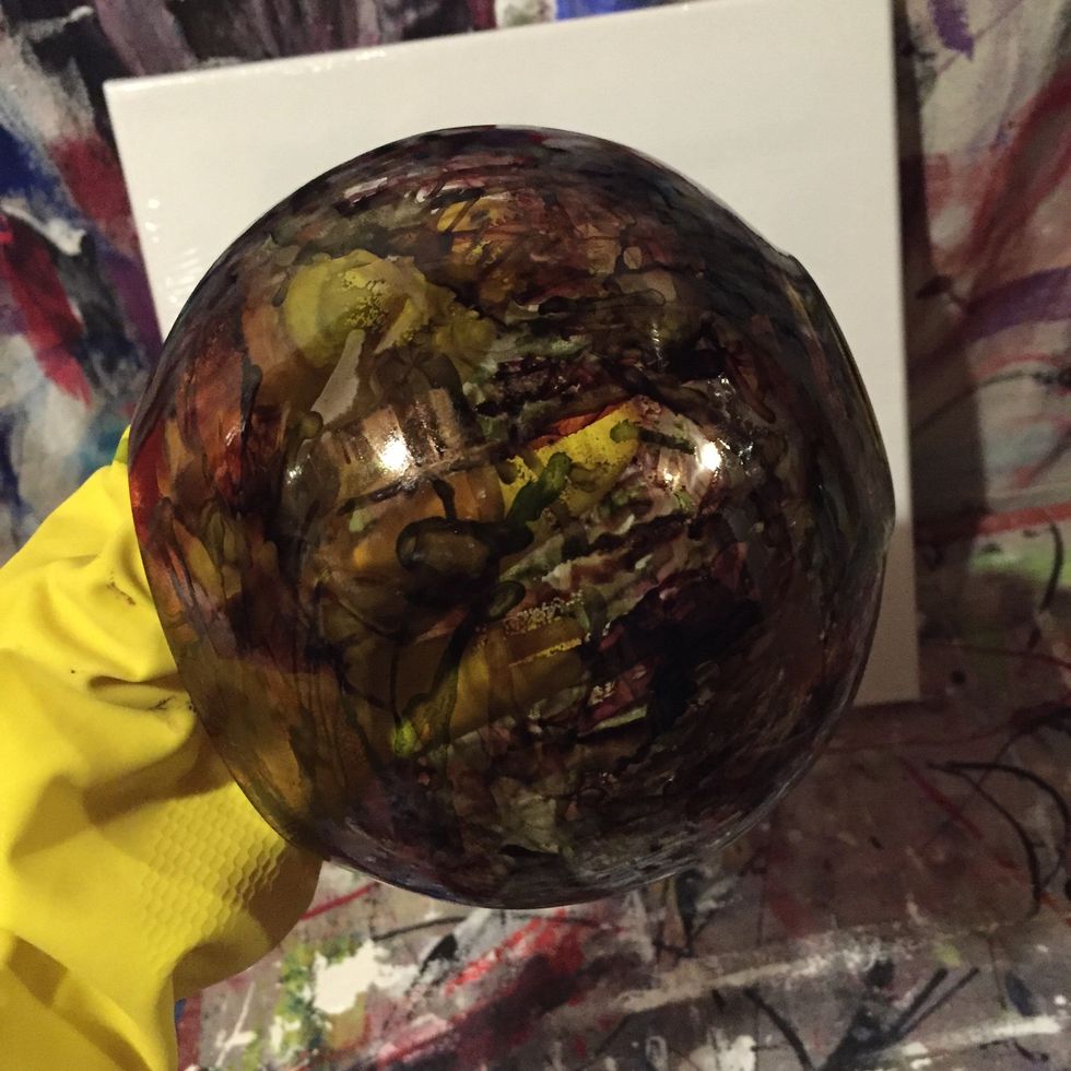 Holding up the glass bowl drop one drop of ink at a time and blow it around the glass until the entire surface is covered. Alternate using different colours until you see the desired effect.