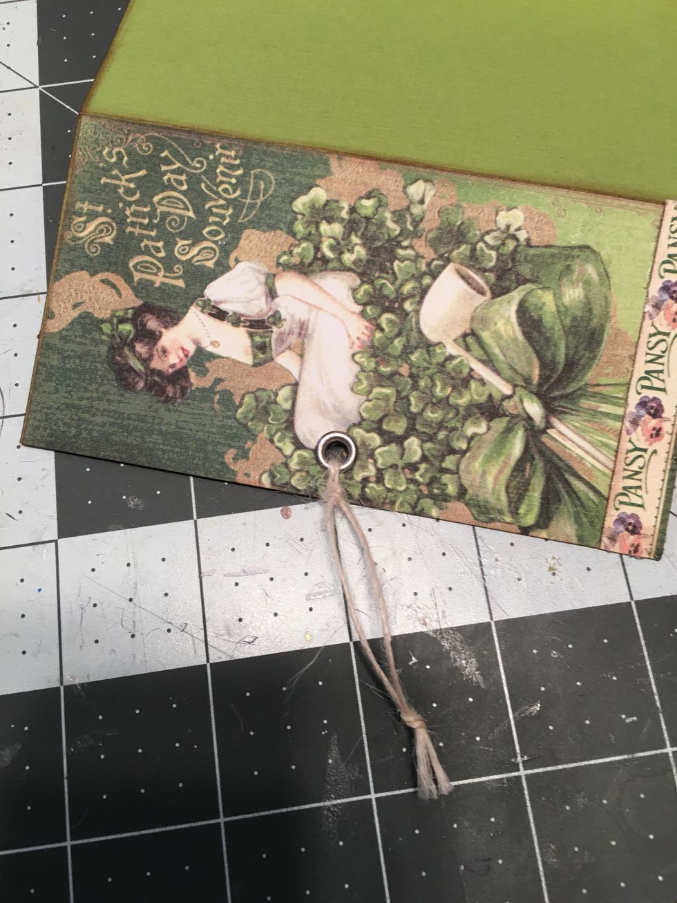 Hole punch and set a sliver eyelet in the first page of the fold out and tie a piece of button string through the eyelet hole to create a pull string for the foldout.