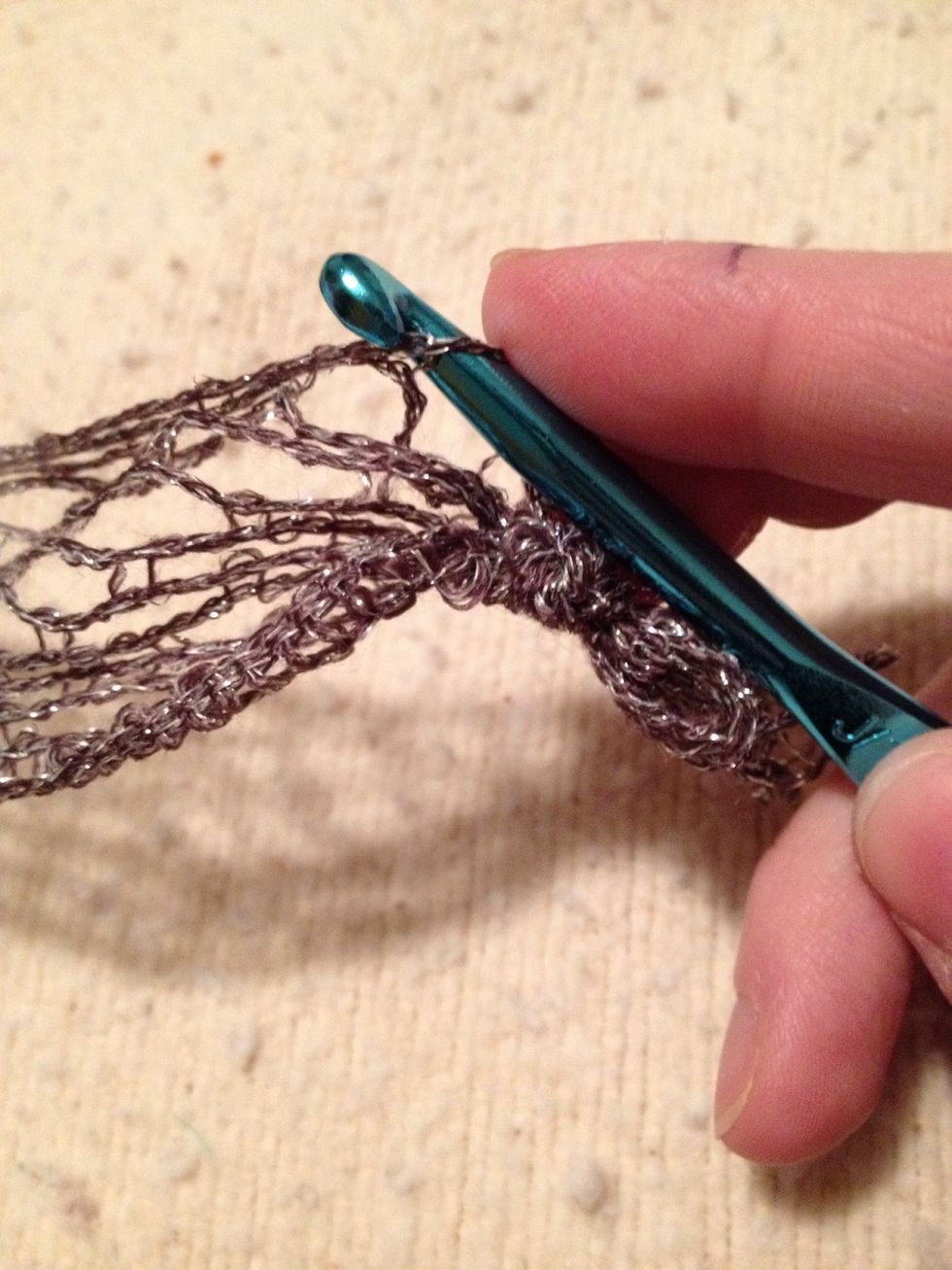 Hook goes through the first loop, in from the front picking up the top string space.
