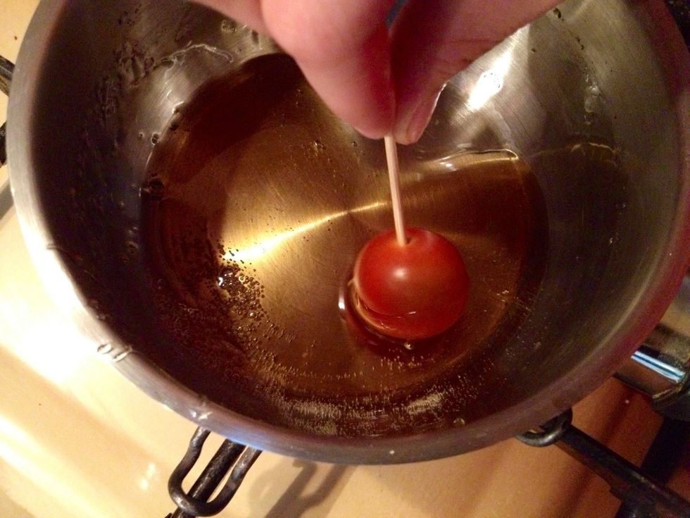 Hors du feu, plongez les tomates au fur et \u00e0 mesure dans le caramel et d\u00e9posez les sur du papier sulfuris\u00e9 ou une feuille de cuisson.