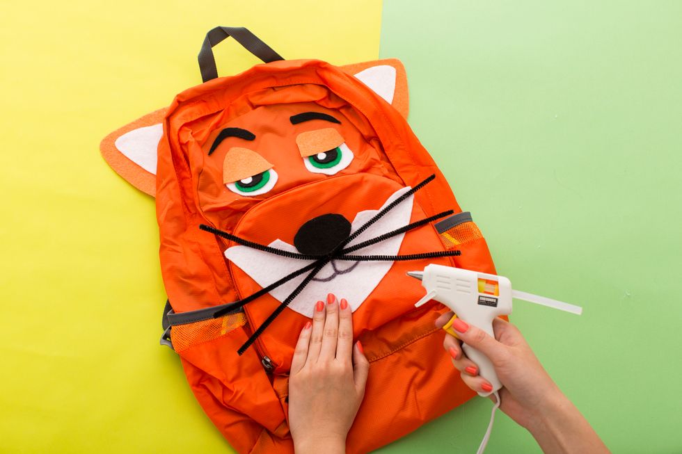 Hot glue Nick\u2019s features to an orange backpack, then let dry. Easy peasy.