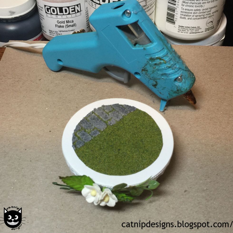 Hot glue the grass and brick circle to the center of the base.
