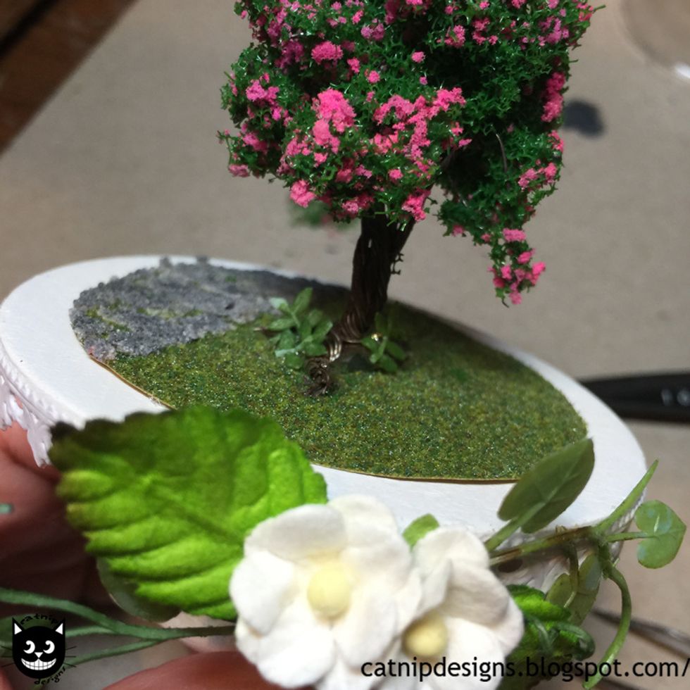 Hot glue them around the tree roots to look like plants.
