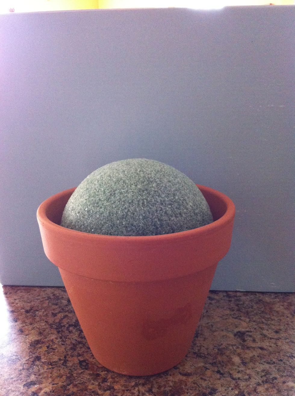 Hot glue your styrofoam ball into your pot