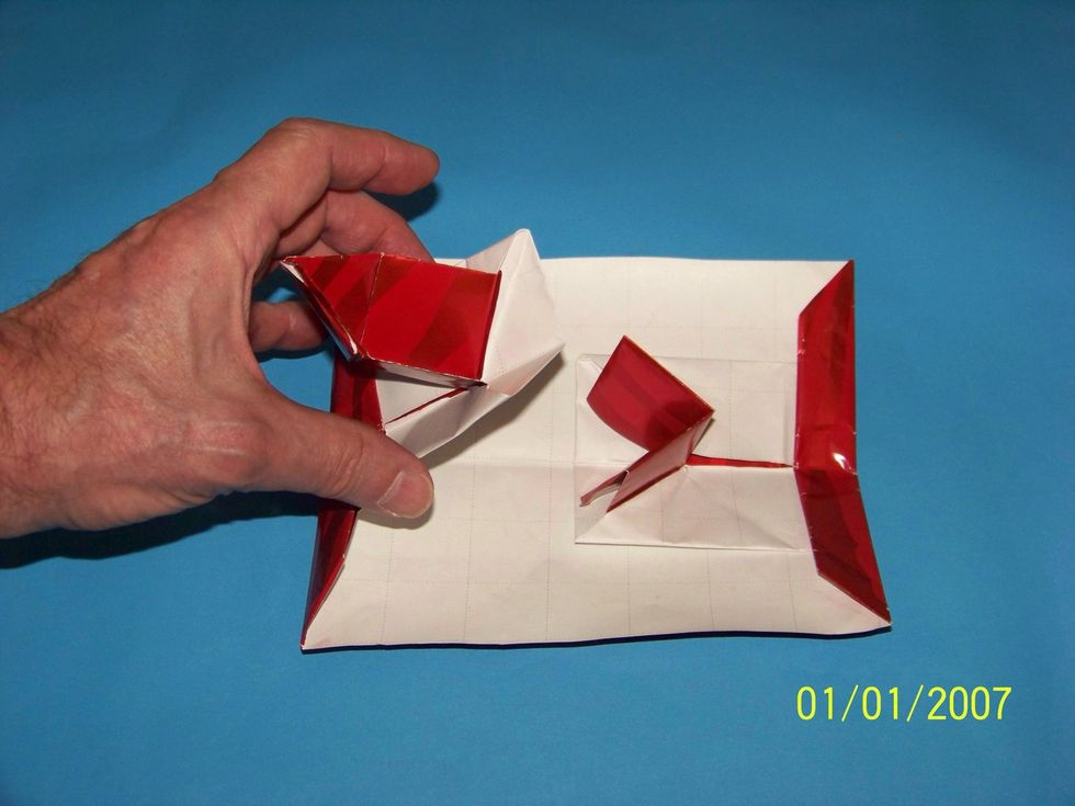 However, pulling on the sides of the card appears to reveal the following: The two parts of the cube are glued to the OUTSIDE edge of the card? Perhaps . . .
