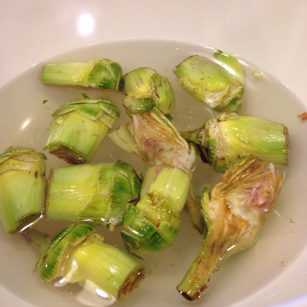 Hull, removing all those tough outer leaves, leaving only the hearts. Slice in half or quarters, and let sit in a chilled water and lemon juice bath - so they don't turn brown!