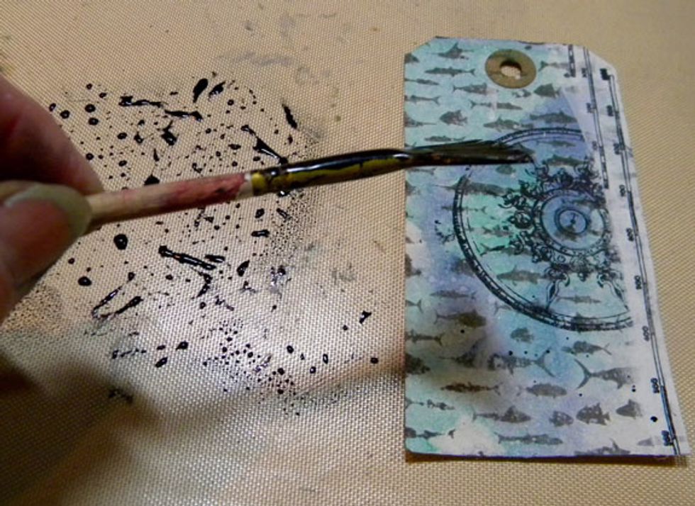 I added a bit of Velvet Cotton to the right edge and more stamps to the background. With the extra spray on the mat, I splattered some onto the tag using a fan brush.