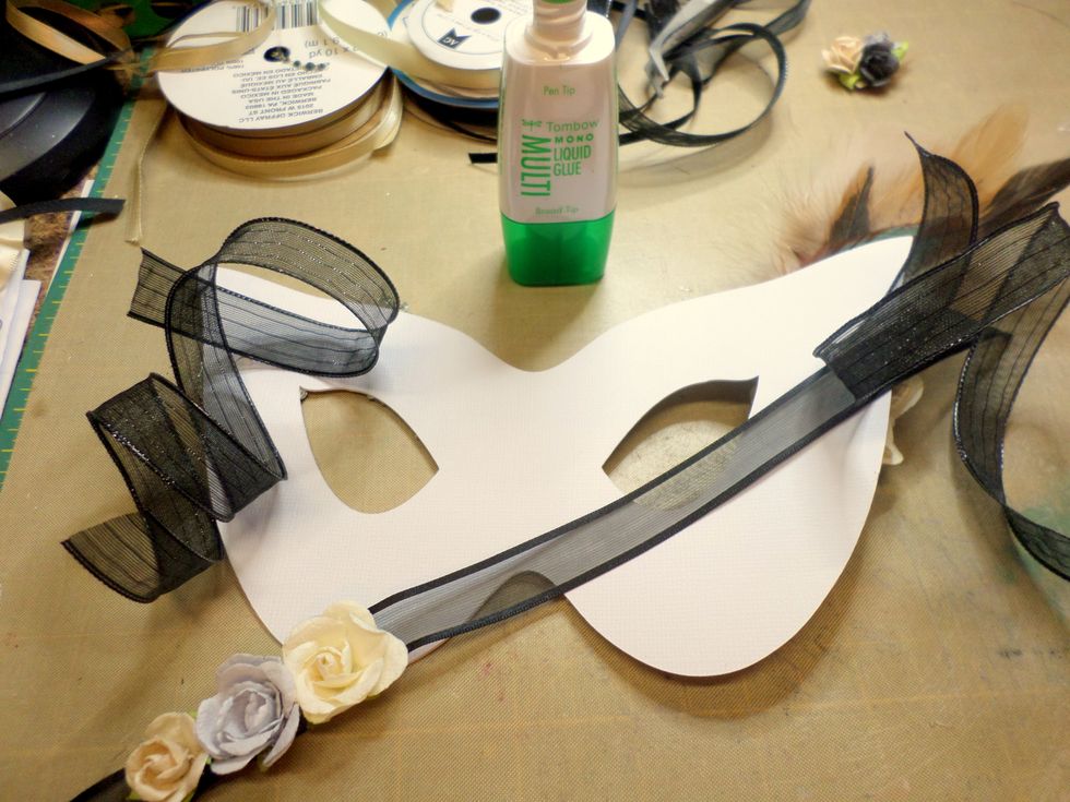 I added ribbons, one to each side so I could tie the mask on and one that I glued flowers to. The ribbon with the flowers is to hang off the mask while you wear it.