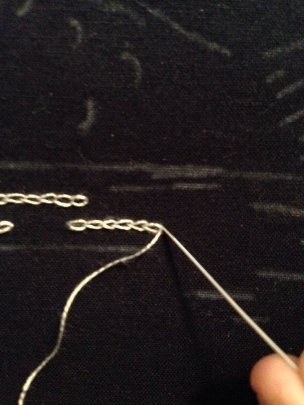 I am done with this line of chain stitches, so to close it off I am taking my needle to the outer edge of my last chain stitch and pulling the thread through to the back.