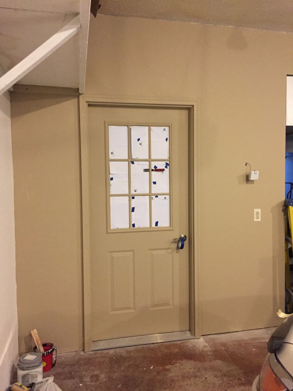 I began painting a solid beige base coat on the wall and steel door. I chose to mask the windows first so there'd be less paint to clean off the glass.