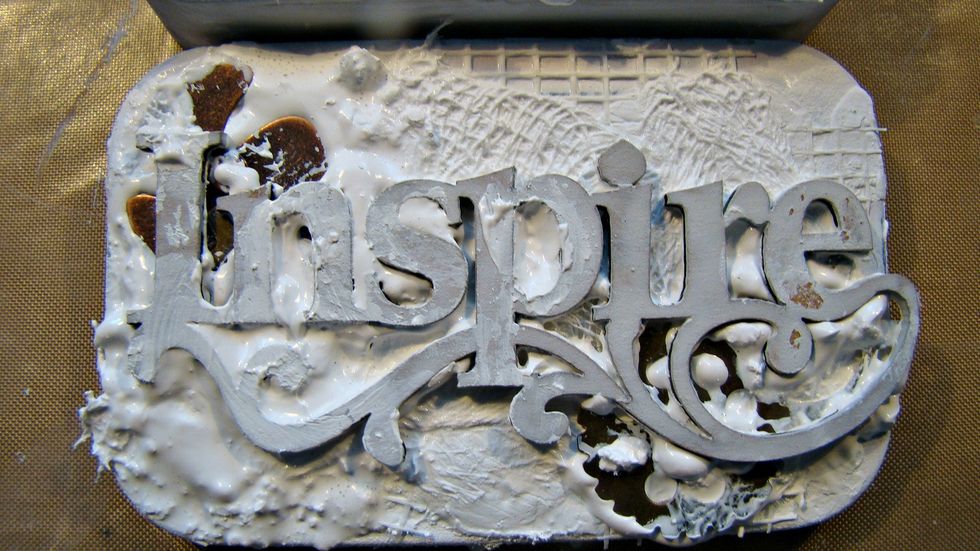 I chose my chipboard title and a few metal embellies and added them to the front cover. Add a coat of white gesso to the entire lid. Put aside to dry.