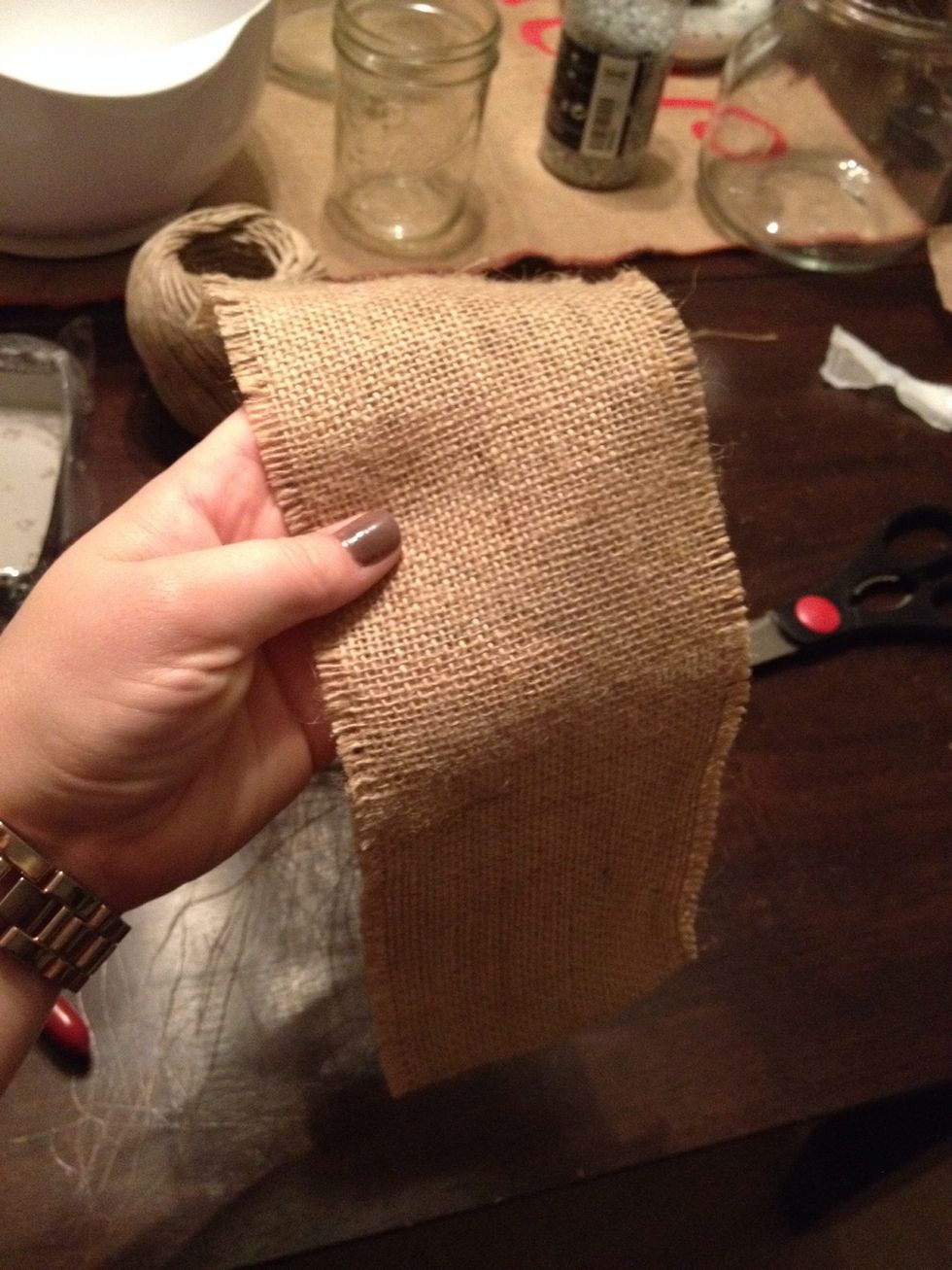 I cut the burlap into strips long enough to wrap around my candles with just enough left to give me a good base for the glue. Once I had my length I folded the burlap in half (because mine was wider)