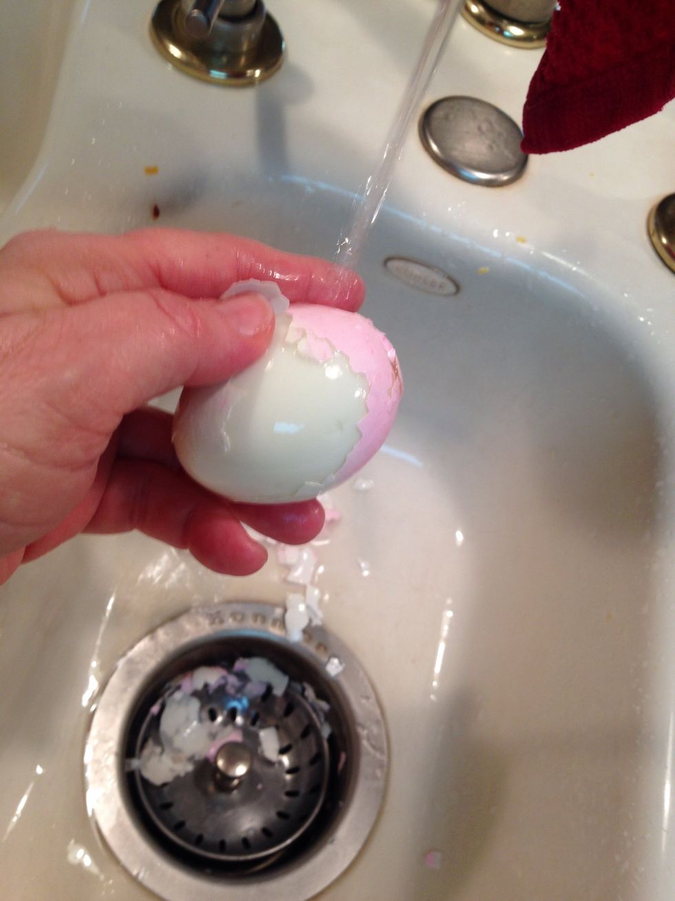 I find it easier to peel hard boiled eggs under running water. Be sure to rinse well to remove any small pieces of shell.