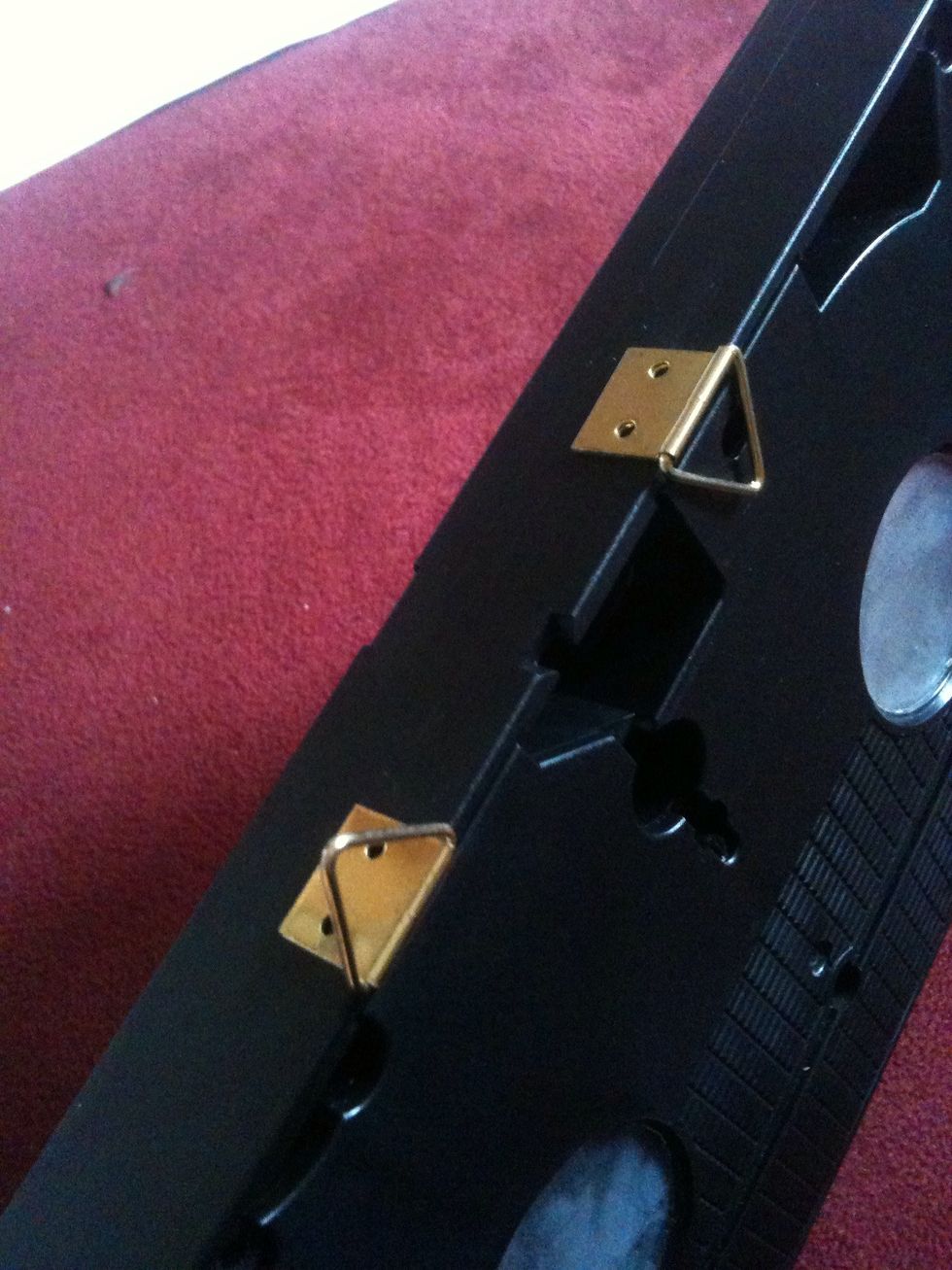 I found These two pieces of metal which are actually made to hold frames in the right place on walls. If you put a bit of super glue on it, they will be perfect for this! :)