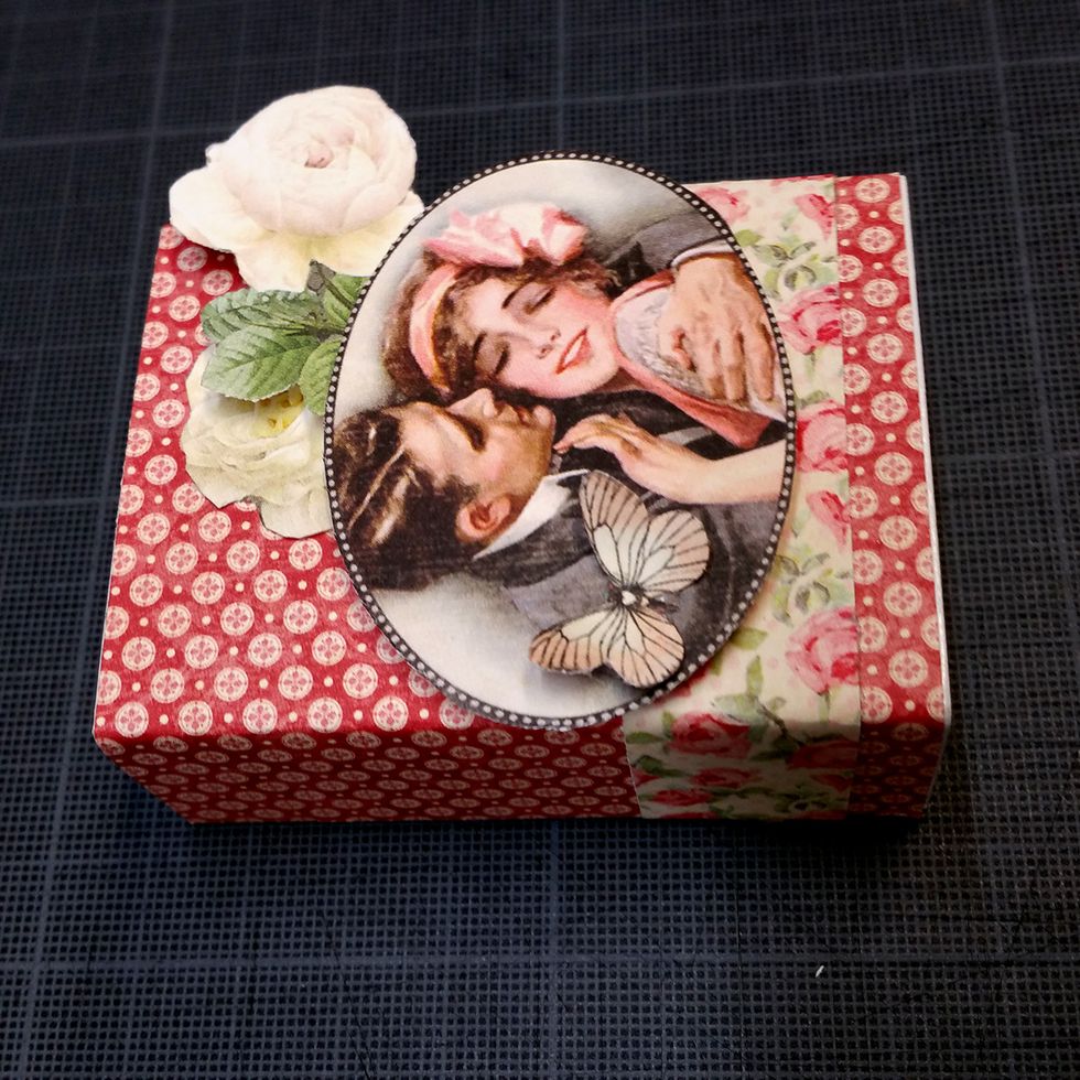 I glued one of the roses directly to the box, a bit under the oval picture. Then I used a foam dot under the other rose, to make some dimension The little butterfly was attached to the oval picture.