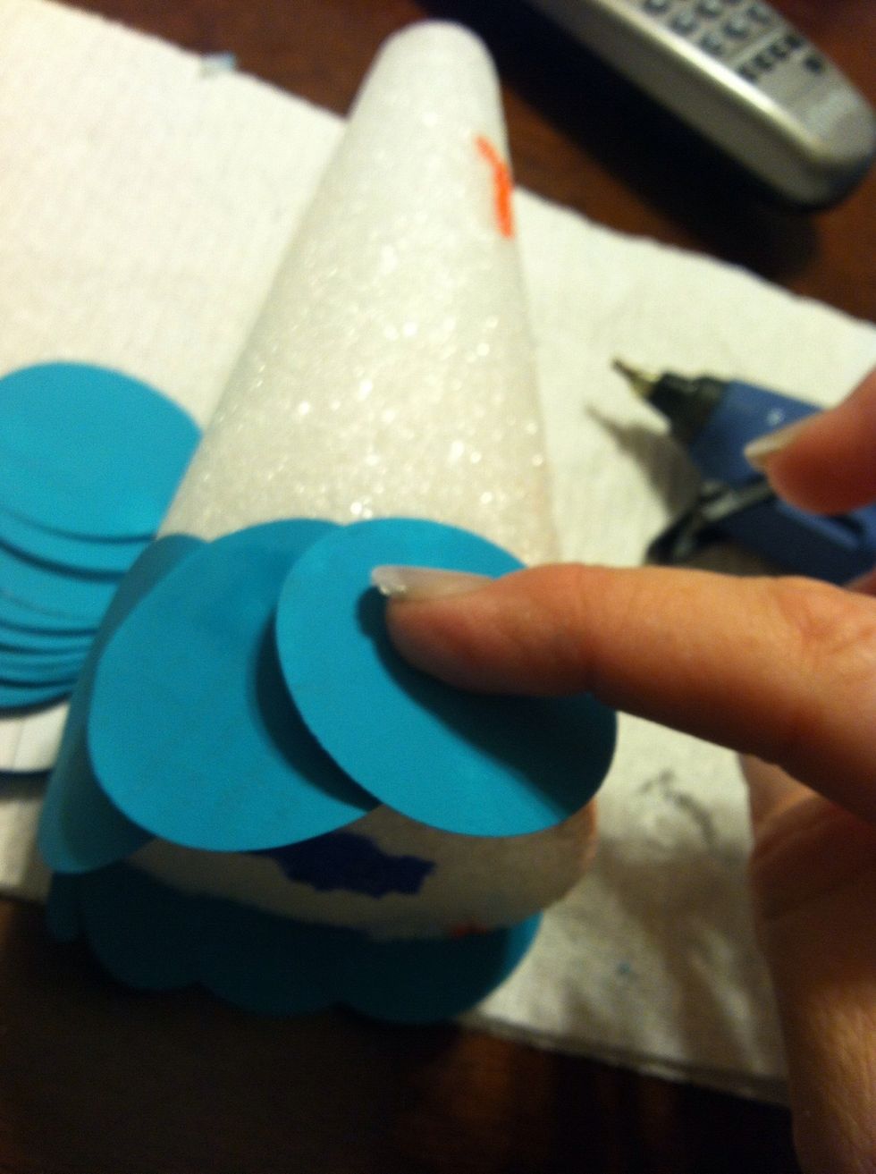 I glued them using the bottom of the cone as a guide to place the first row of circles evenly. The bottom half of the circle was left hanging lower than the cone.