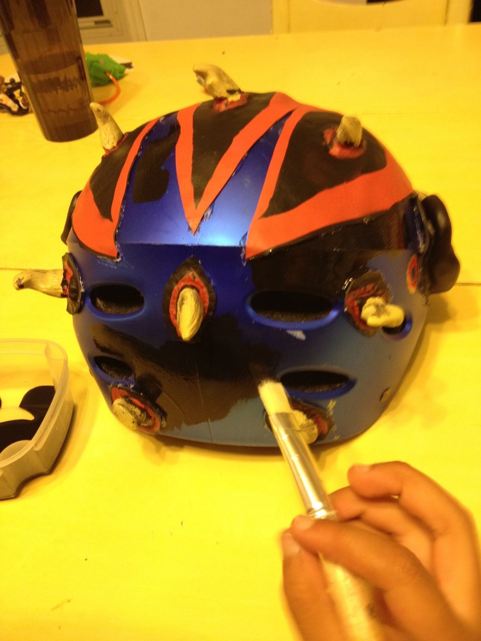 I had some black gloss acrylic paint on hand so I used it to fill in the spaces and cover the rest of the helmet. Here you can see the ears and several of the horns were cut and glued individually.
