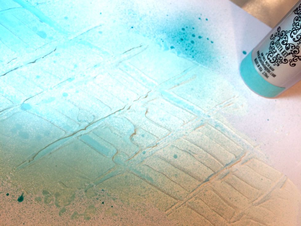 I have the pink elements ready for the layout. Now, it's time for the page, itself. I spray Siesta Key Colorations Spray over the Mud Texture Medium that I previously laid down.