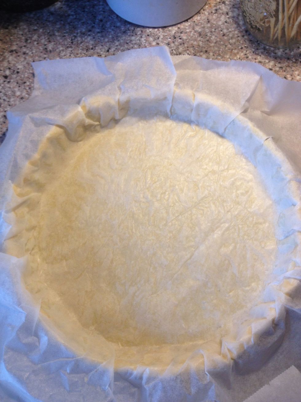 I'm going to bake the pie blind, without filling, and to prevent the edges to slide down I'm going to weigh it down. Place the baking paper from the rolling out exercise on top of the dough.