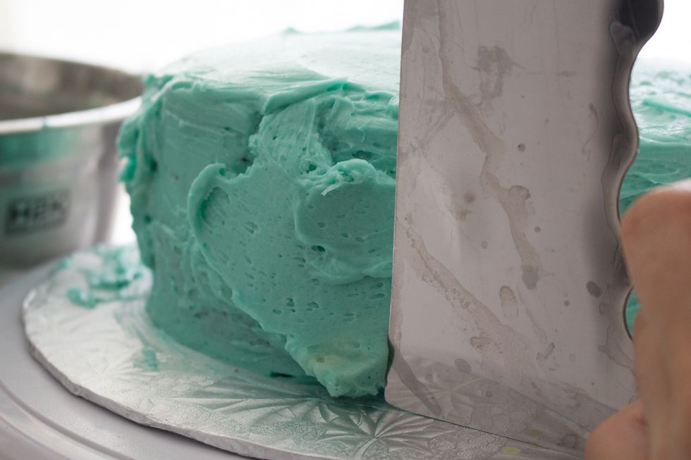 I'm using a bench scraper to smooth out the dirty icing layer of the cake: http://annezca.blogspot.ca/2014/12/how-to-ice-multi-layer-cake.html