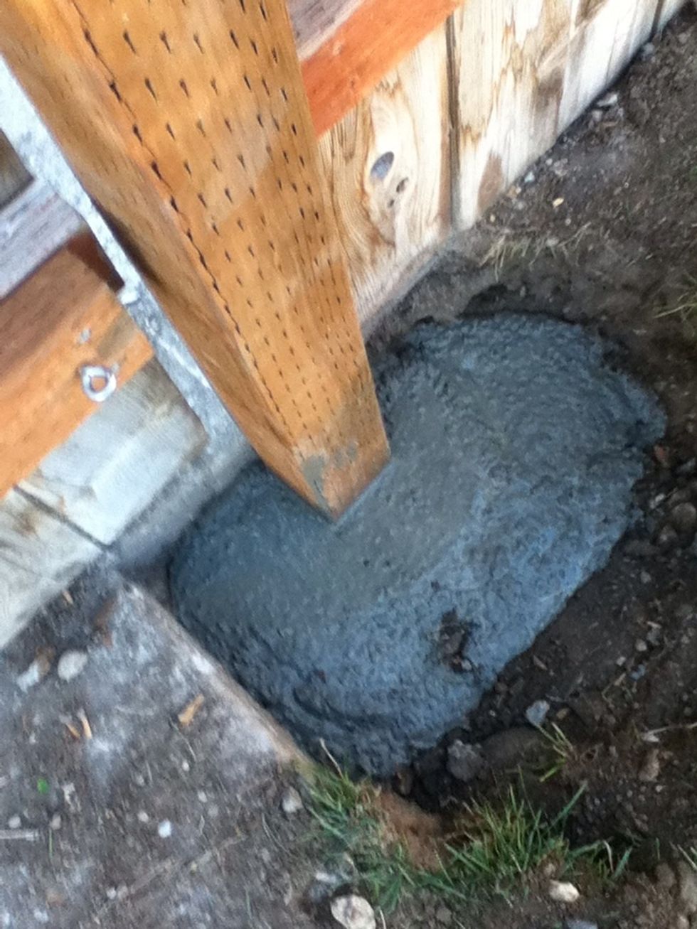 I mixed the concrete in a 5 gallon bucket. Pour into hole and wait. You may need to support the post with boards like in the previous photo. Let dry over night and fill with soil.